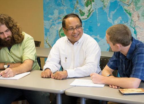 professor sits at table between two students